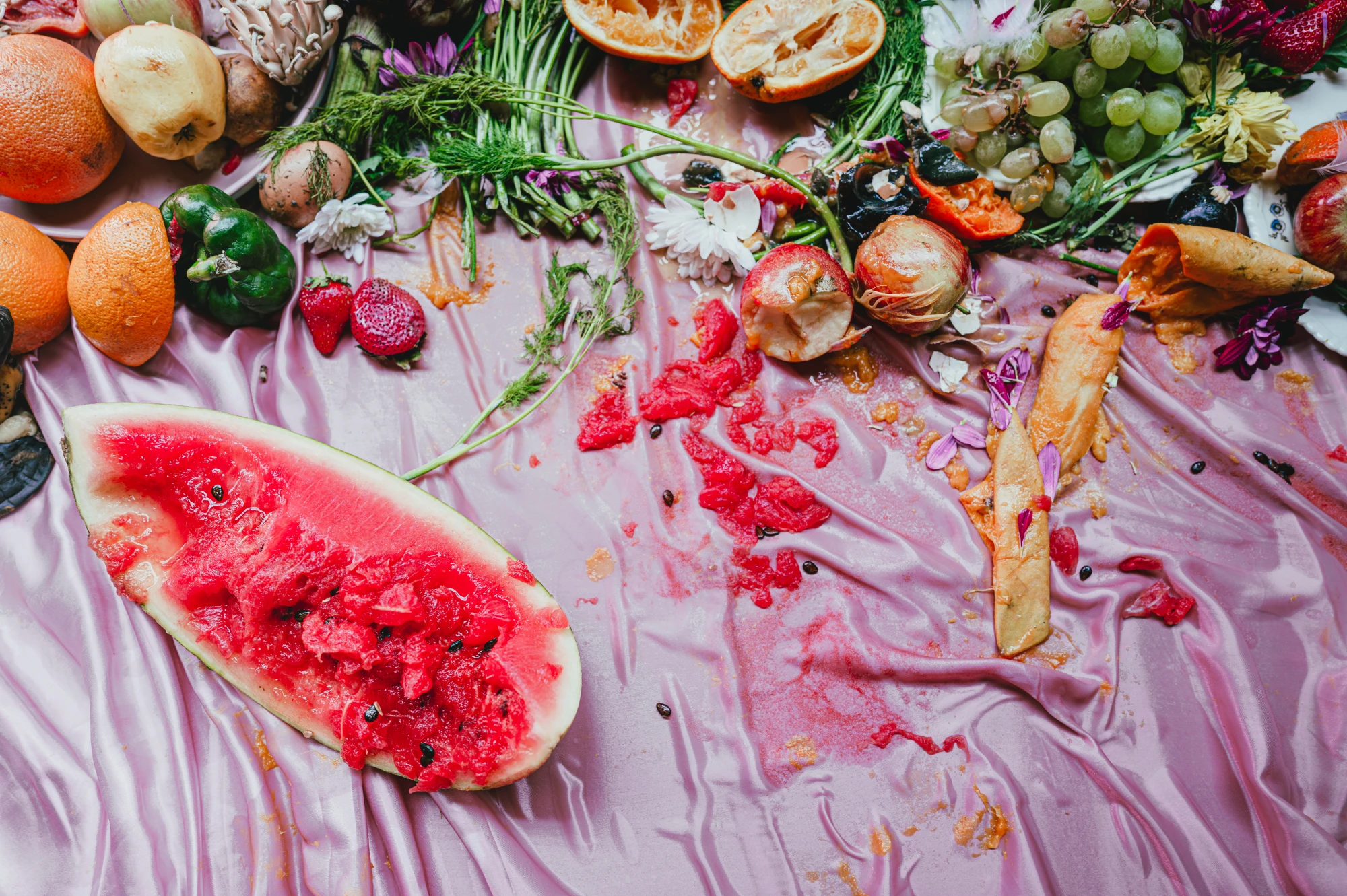 squished and messy fruit across a satin tablecloth, the juices soaking through the fabric.