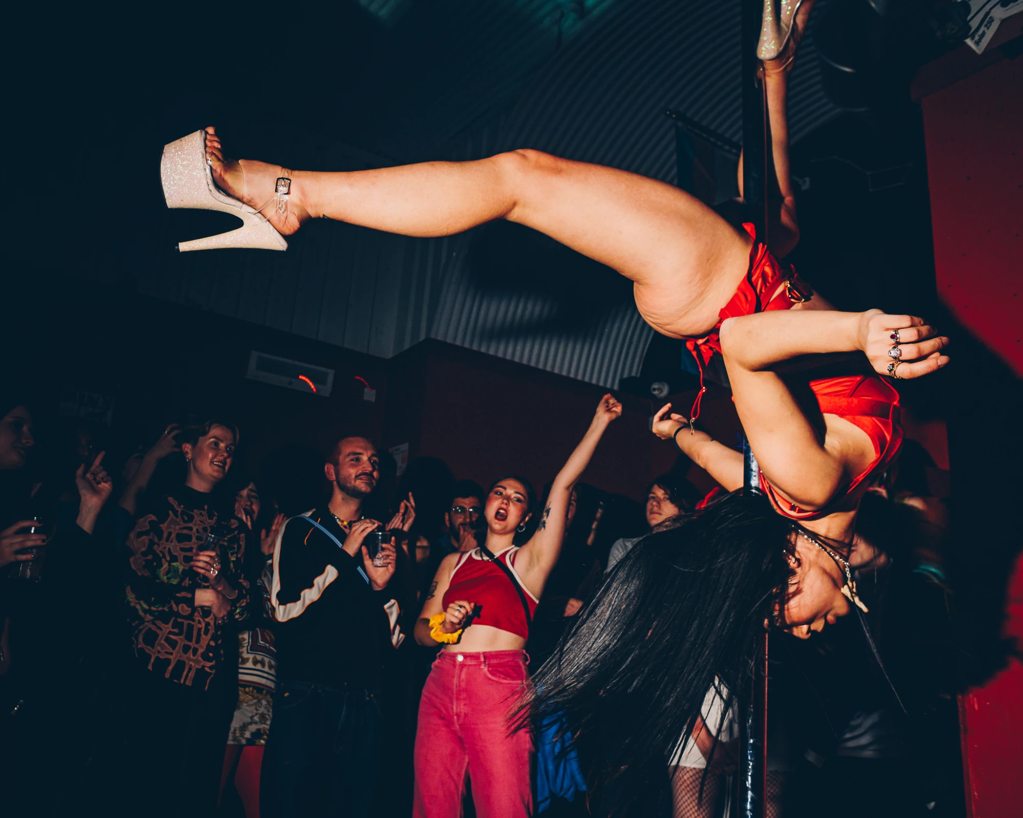 a woman is upside down on a pole as the audience watches on.