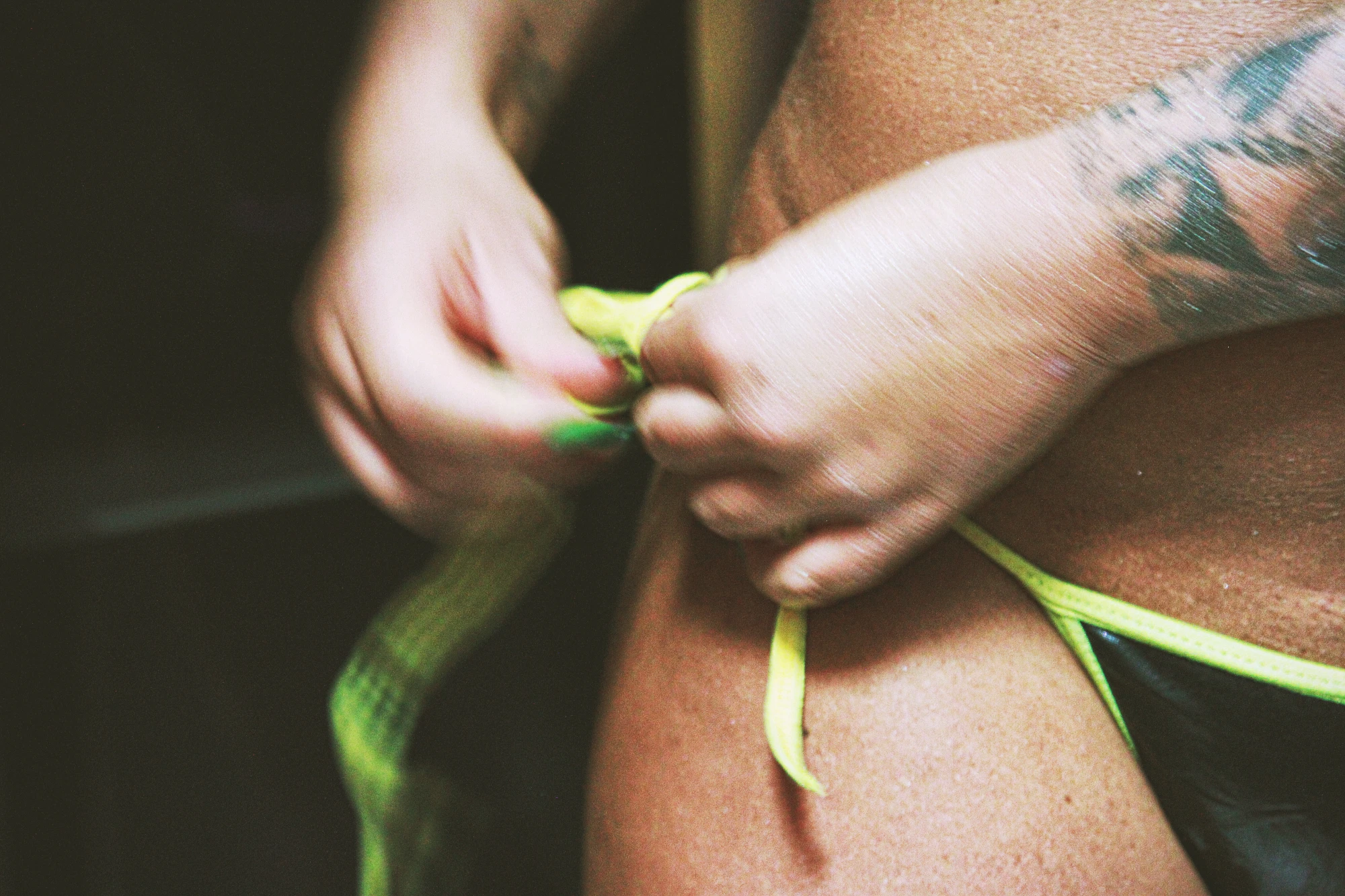 close up of hands tying a bikini botton.