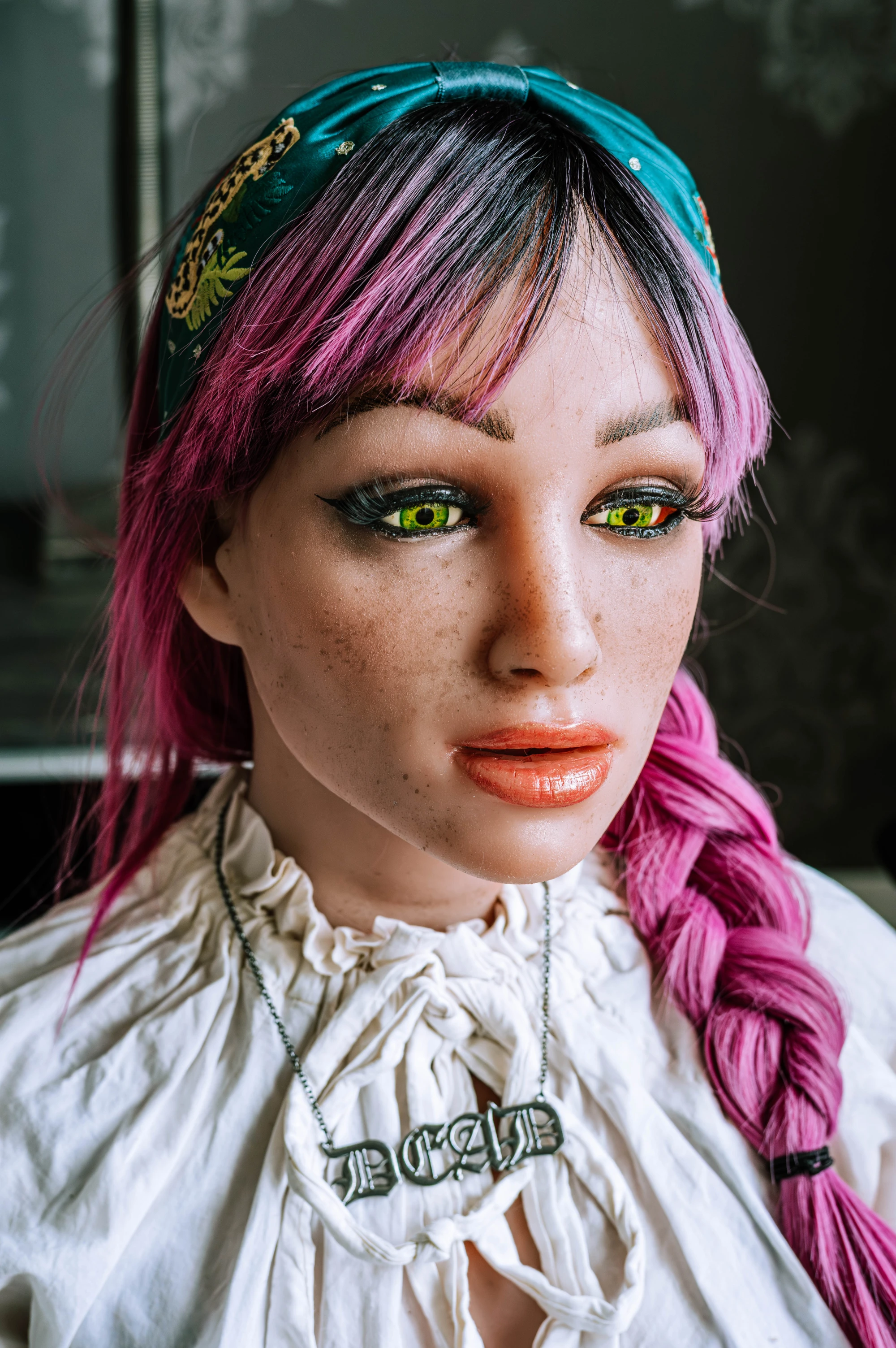 a close up image of a silicone love doll. She has green eyes and a pinkish purple wig on, wearing a white dress.